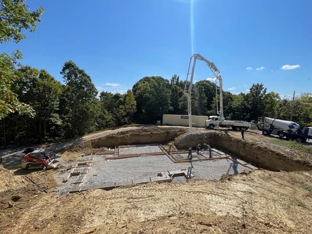 Commercial construction foundation work underway with concrete pouring equipment and crews preparing a large building site.