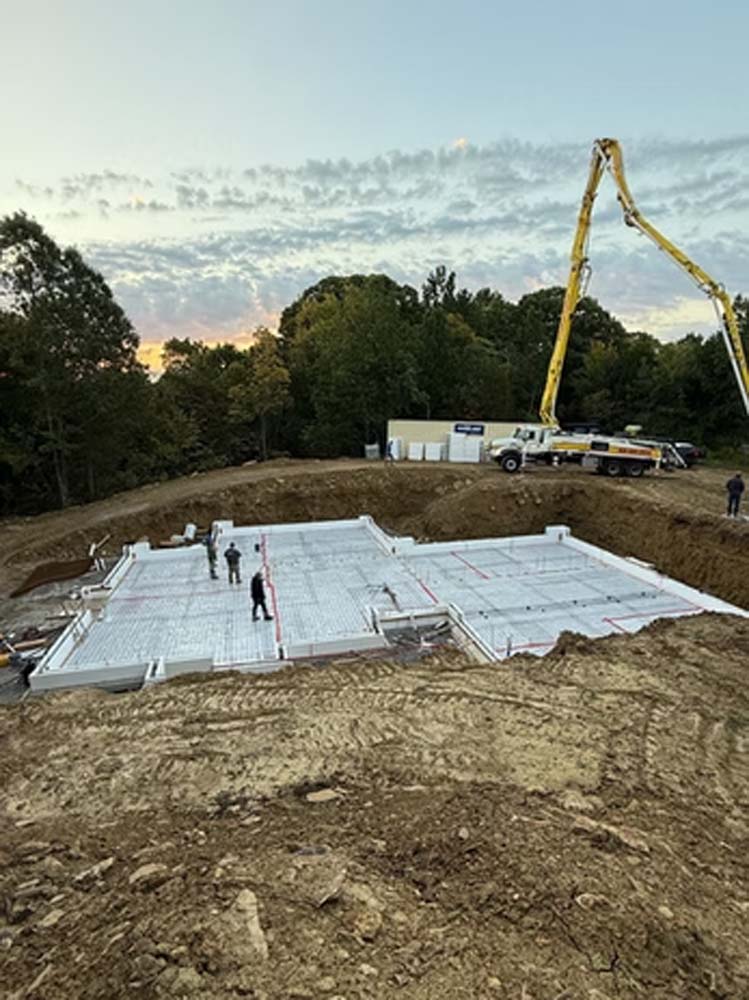 General contracting team preparing an ICF foundation with concrete placement equipment at an active residential construction site.