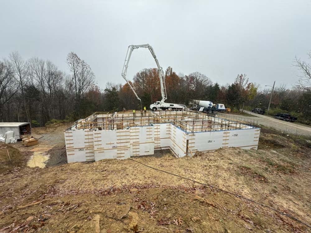 ICF construction project featuring insulated concrete form walls, concrete pumping equipment, and foundation work for an energy-efficient building.